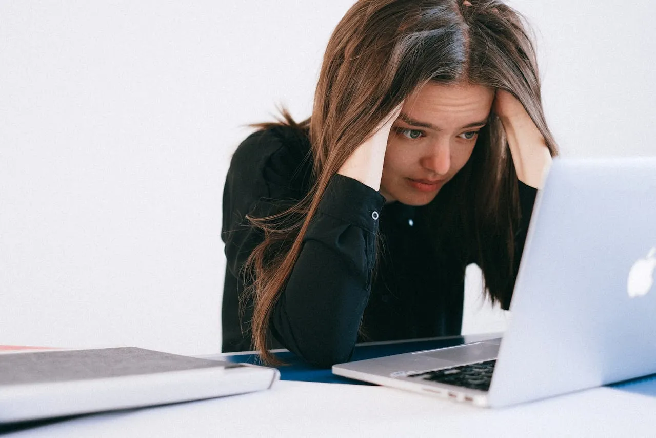 Woman holding head due to headache from looking at a laptop